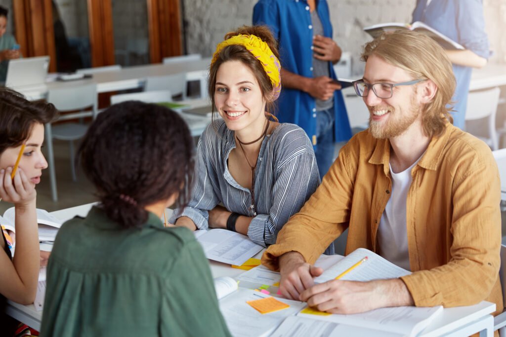 4 students sat at a table smiling and talking