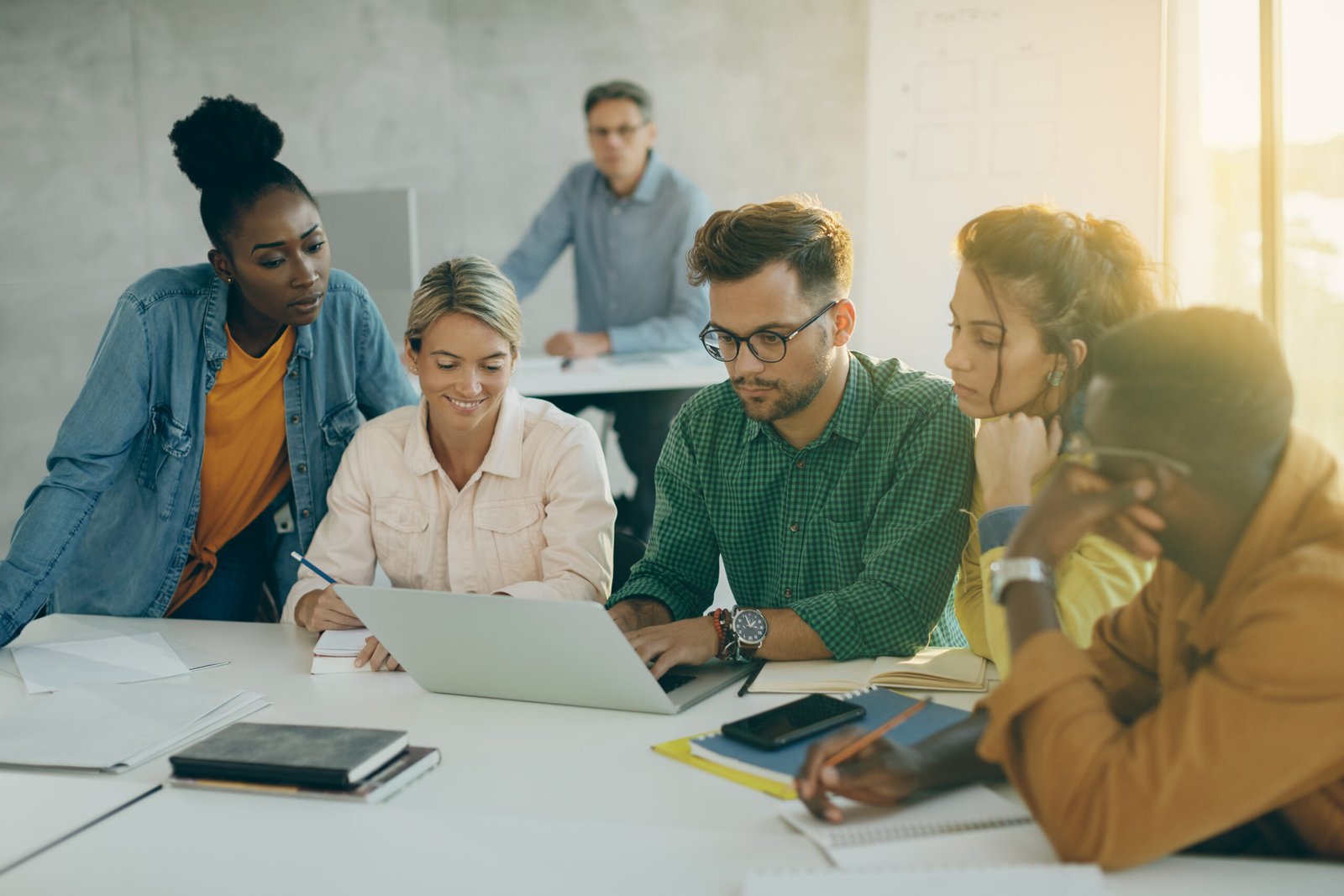Students sat in a group at a desk using a laptop in the classroom.