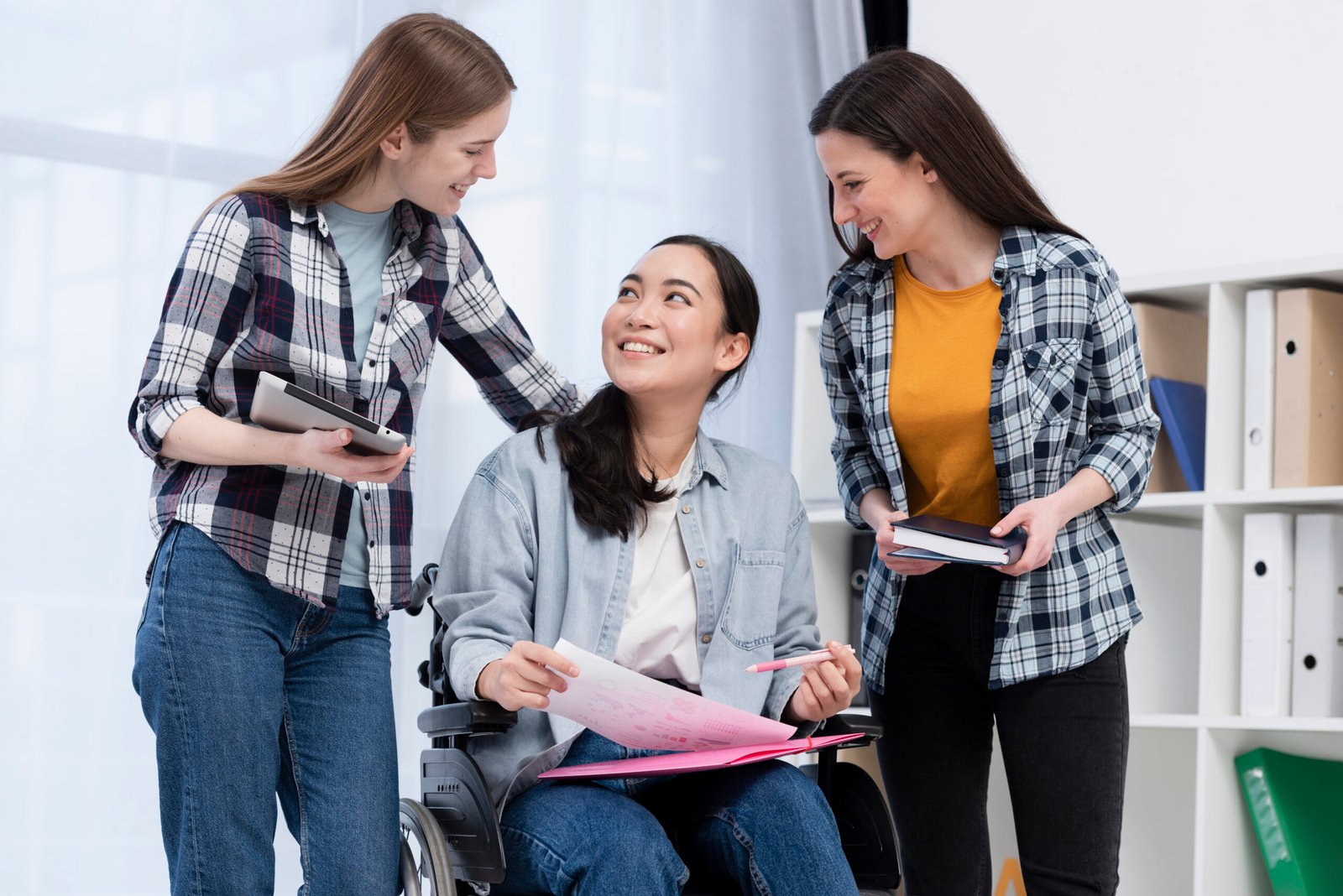 3 friends talking to each other. the one in the middle is in a wheelchair