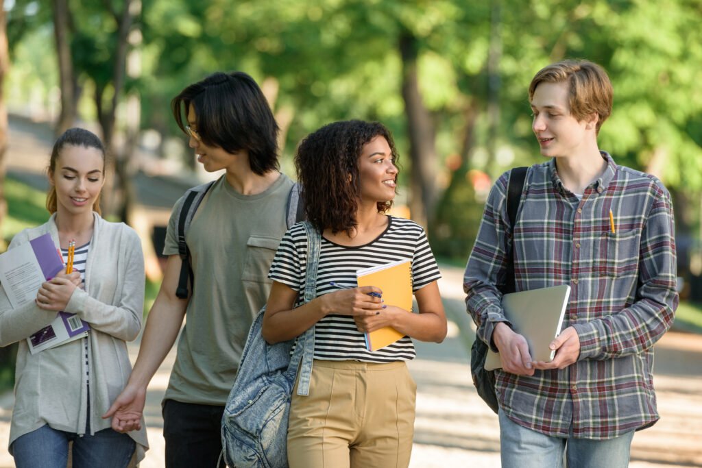 happy students walking and talking. Holding books and a laptop
